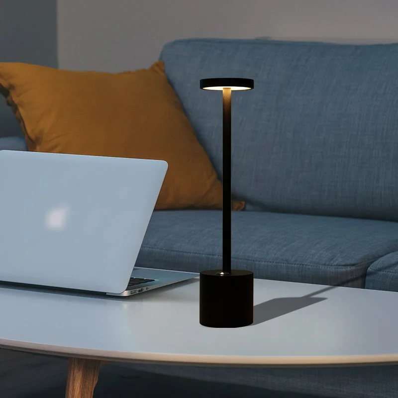 Slim black table lamp casting a warm glow in a lounge setting